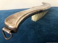 Side angle close-up showing the curved silver-plated handle and the hook at the end for hanging. Shows condition of silver plate with slight tarnish visible.