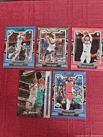 Set of 5 basketball cards including Jalen Suggs, Kyrie Irving, Brandon Boston Jr., Isaiah Livers, and Ja Morant placed on a red cloth background.