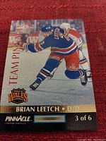 Front image of Brian Leetch Team Pinnacle hockey card showing player in New York Rangers uniform with card series logos and numbering.