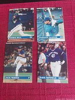 Four Canadian Sportscard Collector baseball cards laid out on a red textured surface featuring Derek Bell, Roberto Alomar, Jack Morris, and Dave Winfield in baseball action shots.
