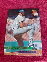 Photo of 1993 Fleer Ultra Randy Johnson Seattle Mariners baseball card lying on a red cloth background. The card shows Randy Johnson pitching in a Mariners uniform.
