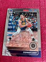 Photo of NBA HOOPS Premium Stock basketball card featuring Stephen Curry in Golden State Warriors jersey, on a red cloth background.