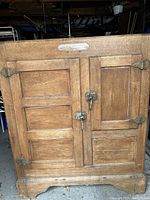 Front view of oak ice box with two swing doors and brass hook latches
