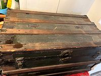 Top view of antique wooden trunk showing wood panels and metal hardware.
