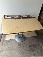 Front and top view of the Brunswick bowling scoring table showing wooden top with slots and metal pedestal base.