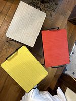 Top view of all three stools/stands showing rectangular shape and colored tops in gray, red, and yellow on wooden floor.