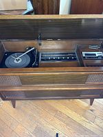 Wide shot of open wooden console stereo showing turntable, AM/FM radio controls, and 8 track player inside.