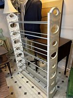 Overall photo of the white metal shoe rack with 8 rows, showing circular cutouts on side panels and horizontal rods for shoe holding.