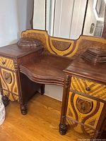 Front angle view of vintage wooden vanity desk showing decorative drawer fronts and curved central seat area