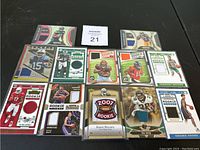 Photo showing 14 football and basketball rookie patch cards with visible jersey swatches in various colors, protected in sleeves and top loaders.