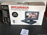 Photo of the Sylvania 9 inch portable DVD player box showing product features including 4 hour rechargeable lithium battery and swivel screen.