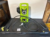 Front view of the green and black Power It PW1600 power washer with power cord coiled on the side and hose attached.