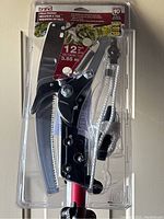 Close-up of the Bond brand tree pole pruner cutting head in original packaging showing steel blade and pull rope.