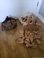 Natural wood soft building blocks arranged on floor including arch, triangles, rectangles, and cylinders in light natural wood finish.