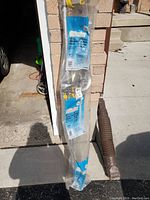 Full view of the clothesline elevator packaged, showing the included rope, metal parts, and label.