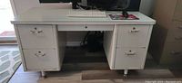 Front view of vintage Steelcase 'Tanker' metal desk showing drawers, adjustable feet, and general condition including visible surface wear and rust.