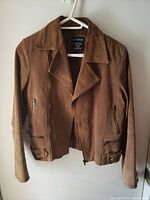 Front view of medium women's brown suede jacket with zippered pockets and front zipper, on white plastic hanger.