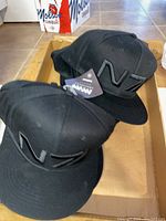 Two black baseball caps with embroidered N7 logos shown in a box.