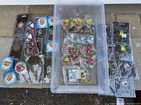 Top view of all 50 pins arranged, showing a variety of cartoon and logo designs, some in plastic bags and mounted on cards.