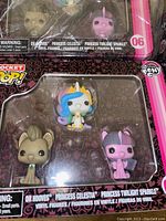 Close-up photo of one set showing the 3 My Little Pony Pocket Pop vinyl figures: Dr Hooves, Princess Celestia, Princess Twilight Sparkle within tin box packaging.
