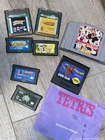 Photo showing a variety of vintage game cartridges for Nintendo consoles and Sega Game Gear, alongside a Tetris instruction booklet.