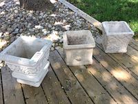 Three square cement planters displayed on outdoor deck