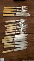 Full view of all cutlery laid out on wood surface showing two distinct handle colors and styles.