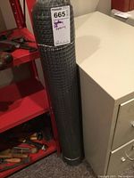 Roll of black plastic mesh fencing standing vertically with label visible on the side