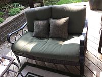 Front view of loveseat on wooden deck with two throw pillows