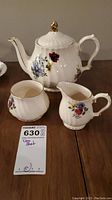 Teapot, creamer, and sugar bowl arranged on table showing floral patterns and overall condition