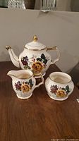 Full tea set including teapot, cream jug, and sugar bowl on wooden surface