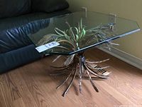 Full view of the vintage table showing the glass top and metal wheat sheaf base in a living room setting.