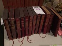 Front view of 12 vintage leather bound books by Sir Walter Scott and others on table