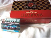 Photo of the closed NASCAR Winston Cup Series 25th Anniversary collectible tin with Pro Set Richard Petty trading card in front showing car #43.