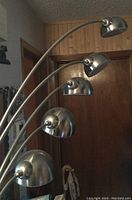 Full view of the five metal dome-shaped lamp heads arranged in a curved arc, attached to a single floor lamp stand.