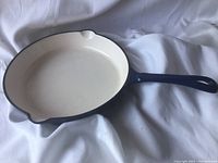 Front and interior view of the round cast iron frying pan showing the white enamel interior and blue enamel handle and rim.