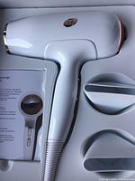 White and rose gold professional hair dryer in packaging with two concentrator attachments and user manual