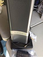 Front view of Lasko electric tower heater showing perforated grille, brand name, base, and power cord coiled at bottom.