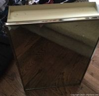 Closed white framed medicine cabinet with mirror on the door, reflecting the surrounding surface.
