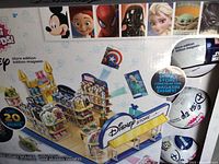 Box front showing completed miniature Disney store displays with Marvel, Pixar, Star Wars, and Disney Princess themes including character artwork such as Mickey Mouse, Spiderman, Darth Vader, Elsa, Baby Yoda.