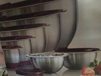 Set of six stainless steel mixing bowls with maroon lids arranged by size