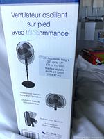 Photo of fan in box showing French and English text describing features: adjustable height from 38 to 47 inches, remote control, oscillation, multi-tilt.