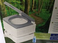 Photo showing the portable toilet with closed lid in an outdoor forest setting, highlighting the two-section design and included deodorizer sample.