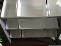 Top view of nine white plastic storage bins arranged in three rows on the rack