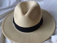 Front view of beige straw hat with wide brim and black ribbon band.