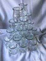 Stacked pyramid formation of clear glass tea light holders against a white fabric backdrop, showcasing their size and shape.