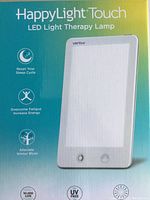 Front packaging showing product name HappyLight Touch, brand Verilux, and key benefits: reset sleep cycle, increase energy, alleviate winter blues.