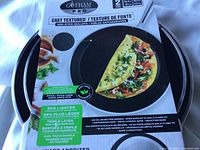 Photo of packaging showing Gotham Steel Pro 2-piece set with a 10 inch and 11.5 inch non-stick skillet featuring a cast textured surface and an omelet.