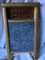 Front view of the antique washboard showing wooden frame and metal scrubbing surface with manufacturer stamp on top wood panel.
