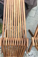 Close-up front view of one wooden beach chair, showing slatted seat and backrest with wooden framing and wear marks.